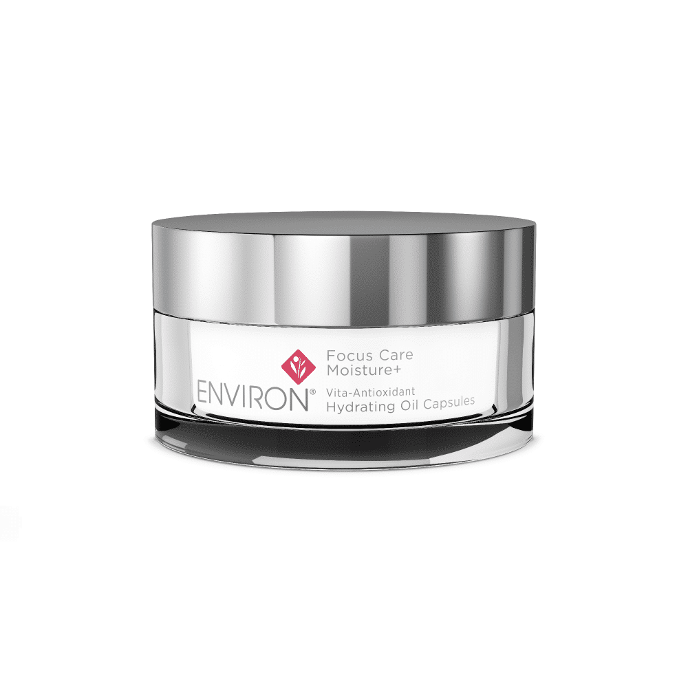 A small, round, silver-lidded container of Environ Focus Care Moisture+ Vita-Antioxidant Hydrating Oil Capsules. The label is white with the product name and branding in grey and pink font. Packed with antioxidants and vitamins, the reflective container stands out against a plain white background.